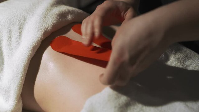The masseur sticks teips on the woman's stomach