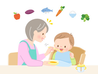 赤ちゃんに離乳食を食べさせるシニア女性