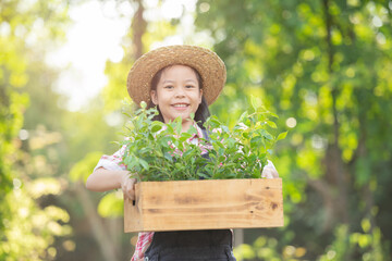 Cute little child girl with seedlings. volunteering, charity, people and ecology concept - volunteers hands planting tree seedling in park. holding a box with plants.