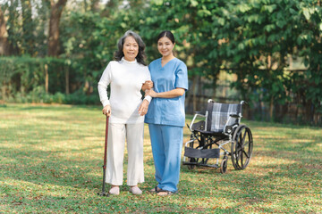 Young asian care helper with asia elderly woman on wheelchair relax together park outdoors to help and encourage and rest your mind. using crutches and cane help support yourself to walk