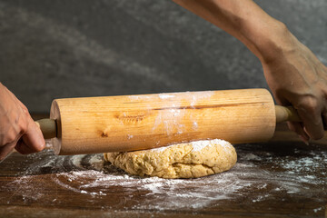 Bakery - A person prepares bread flour on a wooden table with a rolling pin in a dough