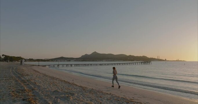 Mujer corriendo por la playa con amanecer y atardecer