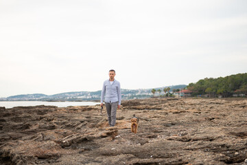 Man walking with his dog during the walk by rocky seacoast - 586045374