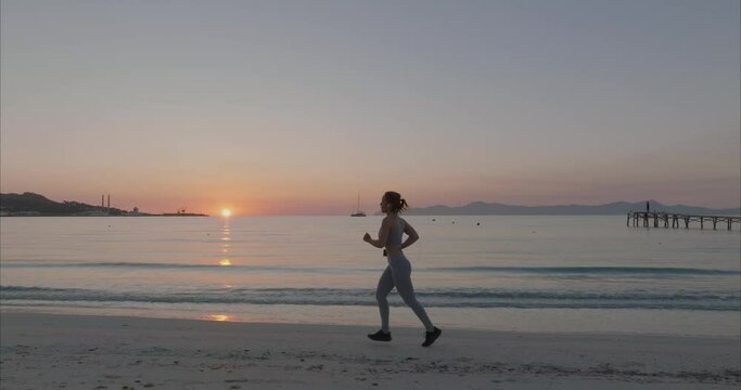 Mujer corriendo por la playa con amanecer y atardecer