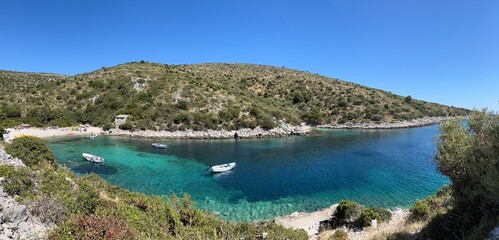 Panoramic view of beach and boats on the crystal clear blue and turquoise waters of Brbinjšćica Bay on Dugi Otok Island off the coast of Zadar in Dalmatia, Croatia
