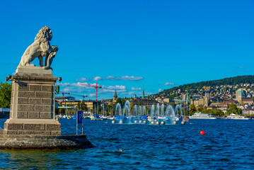 Panorama of Siwss town Zuerich behind a lion statue and Springbrunnen fountain