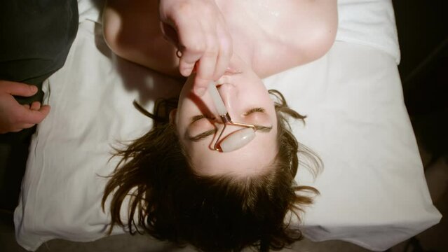 Woman getting facial massage with jade facial roller
