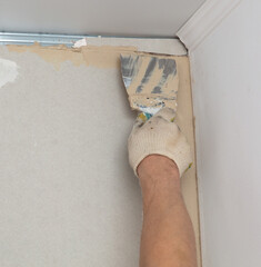 A worker is plastering a wall with a plastering tool.