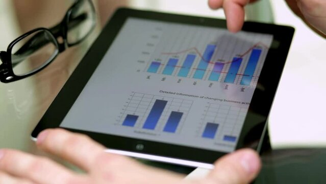 Businessman using a tablet to analyze data points and graphs - isolated