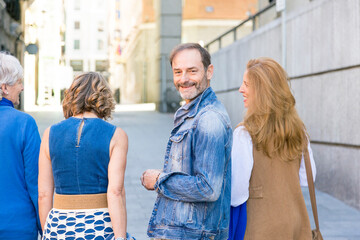Obraz premium middle-aged man looking at the camera while his group of friends walk by
