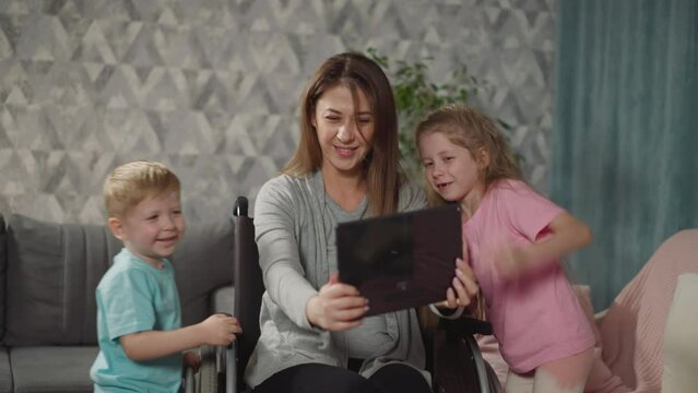 Happy mother takes selfies with active kids on modern tablet