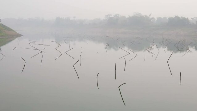 flying low above a lake ful of fish traps in the early morning fog