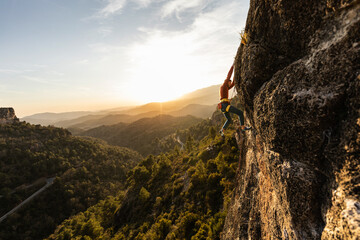 man climbing at sunset in the mountains with the forest in the background, copy space, business, security, trust