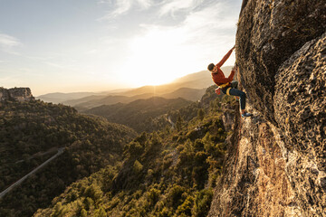 man climbing at sunset in the mountains with the forest in the background, copy space, business,...