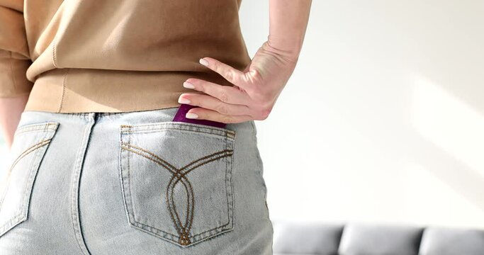 Woman takes condom out of jeans pocket with hand in room