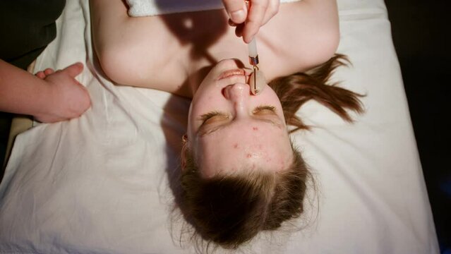 Woman getting facial massage with jade facial roller