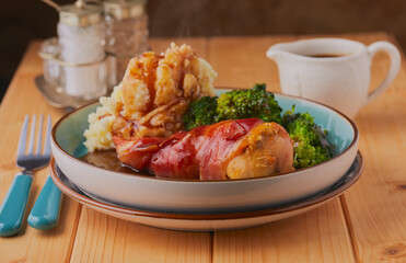 Chicken breast wrapped in bacon served with potatoes and broccoli.