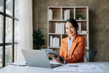 Young beautiful woman using laptop and tablet while sitting at her working place. Concentrated at work..