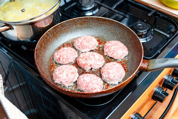 Raw meatballs frying in the pan at kitchen home.Selective focus.
