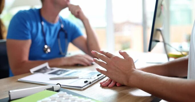 Female patient complains to doctor about bad health sitting at table in hospital office. Man with stethoscope listens to concerned woman slow motion