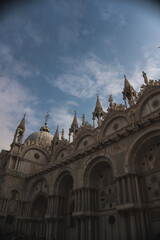 Fototapeta premium Basilica di San Marco's grandeur captured in a vertical wide-angle shot, complemented by a serene blue sky with fluffy white clouds.
