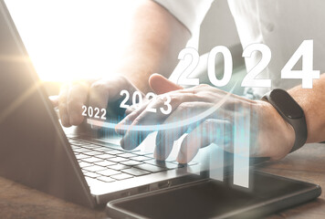 2024 new year. Business plan 2024 new year. Man working on laptop with growth chart 2024. Start new...