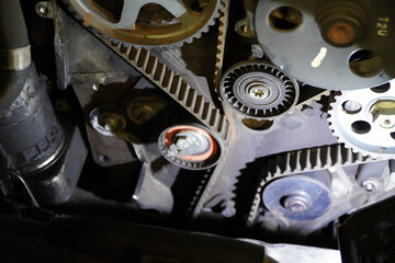 Old timing belt with rollers mounted on an old engine in the garage. concept of changing the timing belt at certain distances.