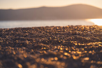 Beautiful seascape, pebble beach in the glare of the sun at sunset. Summer vacation background