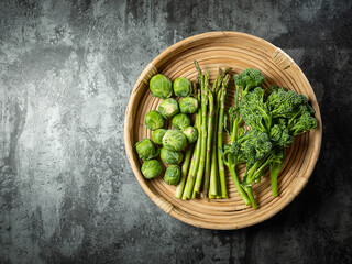 Baby broccoli, brussels sprouts and asparagus on wooden plate