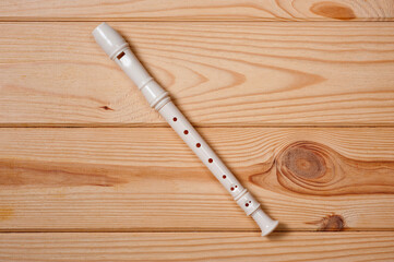 Block flute wind musical instrument photographed on a wooden surface.
