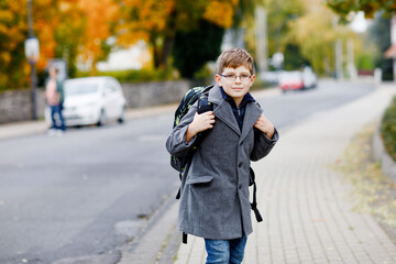 Happy kid boy with glasses and backpack or satchel. Schoolkid in stylish fashon coan on the way to...
