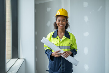 Portrait of woman engineer with full version enineering cloth, holding roll of plan paper looking to camera with smile of happiness, teeth smile.