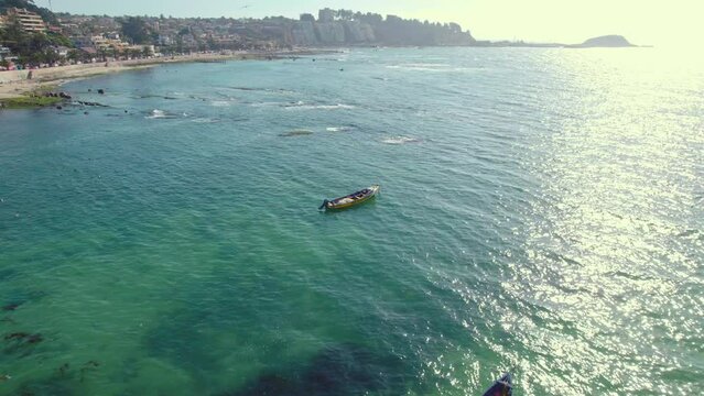 Aerial shot over boats floating off the coast from the stunning Pejerrey beach, Chile 