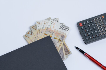 Pieniądze, kalkulator i notatnik leżące na białym biurku