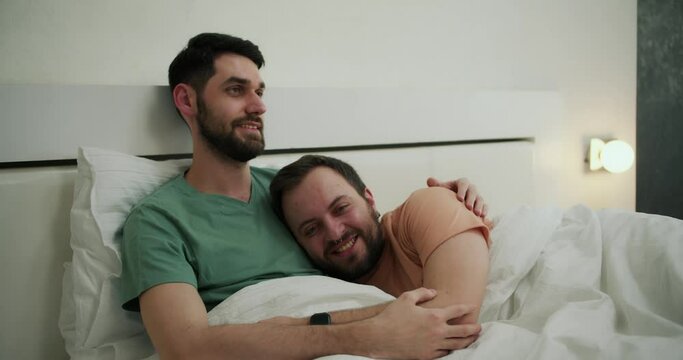 Happy homosexual men in hugging in bed in morning