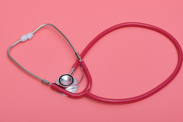 Czerwony stetoskop medyczny na różowym tle - obrazy, fototapety, plakaty