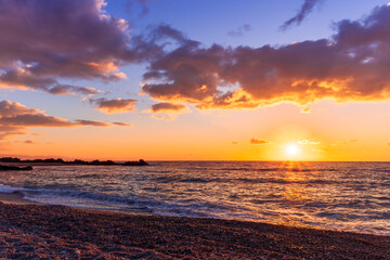 empty beach with surf during beautiful sunrise or sunset with surf, clouds and golden sun