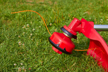 Brush cutter with the grass,a new red mower lies on the grass, work in the garden, mow the grass