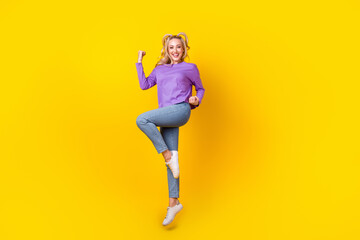 Fototapeta na wymiar Full body photo of attractive young woman jump raise fist celebrate dressed stylish violet outfit isolated on yellow color background