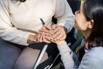 Family relationship Asian senior woman in wheelchair with happy daughter holding caregiver for a hand while spending time together - obrazy, fototapety, plakaty