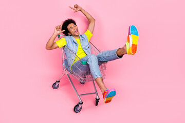 Full length photo of positive glad crazy man wear bright stylish clothes sitting cart have fun low...