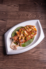 grilled bbq fresh whole seafood squid sooting octopus with spicy samba chilli sauce and petai smelly bean vegetables on banana leaf plate wood table asian halal food menu