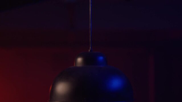 Close up view of a ceiling lamp being lit. Dark interior, basement, interrogation room, poker night