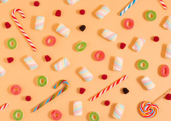 Pattern of various sweets, gummy candies, marshmallows and lollipops on a yellow background. Colored party concept. Flat lay.