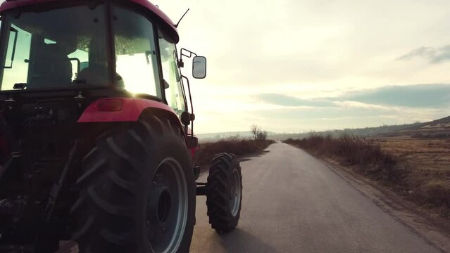 Tractor on a rural road among the fields at sunset