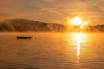 Mglisty wschód słońca nad jeziorem Żywieckim w bardzo ciepłej tonacji.