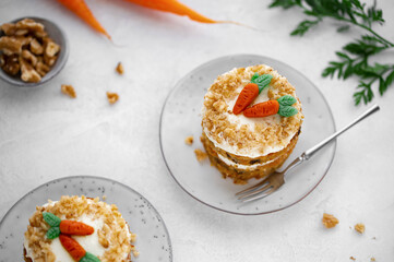 Easter Carrot cake with cream cheese frosting and marzipan decorations on a white stone background for festive dinner. Small easter bento cake. Fresh homemade carrot dessert. Traditional Easter food.