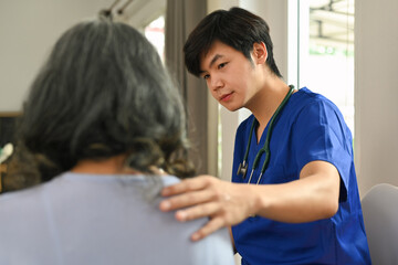 Doctor touching shoulder comforting upset senior patient after medical diagnosis at clinic. Elderly healthcare concept