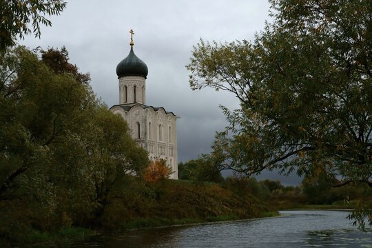 Part of The Church Pokrov on the Nerl is visible in the depths of the trees, in the foreground the Nerl River, the city of Vladimir, Russia