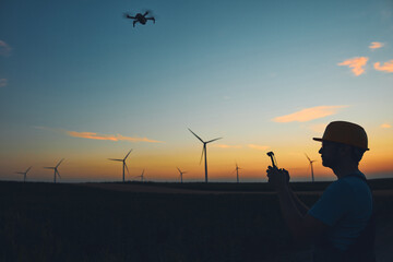 Engineer mechanic using drone for inspection in a windmill farm park.